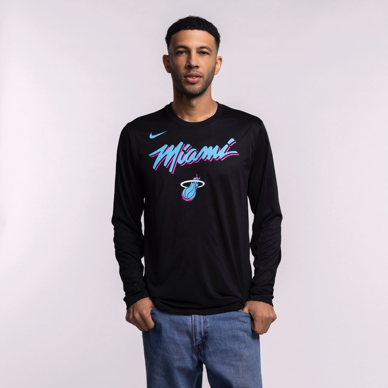 A man faces the camera wearing a men's size L Nike Miami HEAT Original Vice Nights Legend Long Sleeve Tee, featuring colorful 
