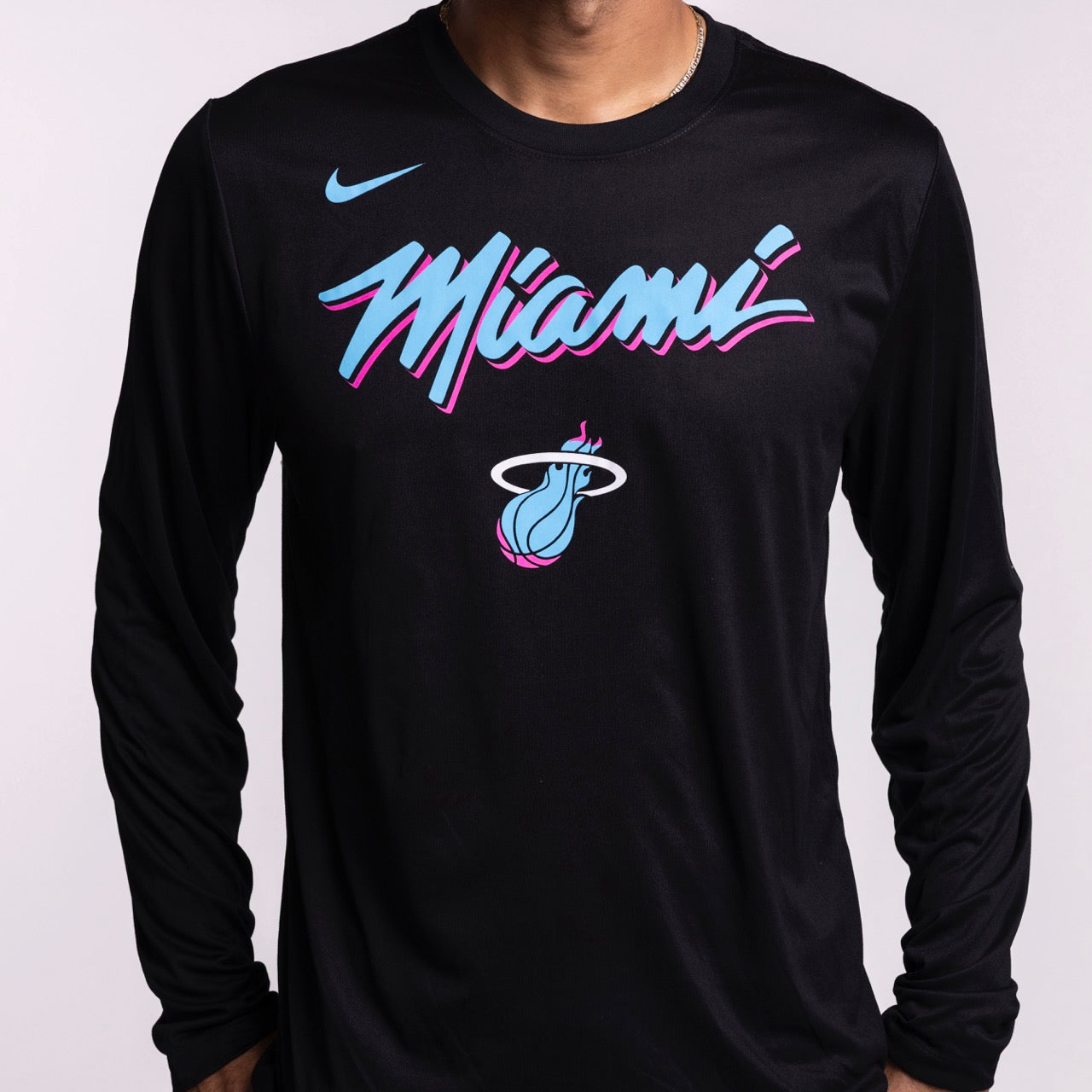 A person is shown from the torso up wearing a black Nike Miami HEAT Original Vice Nights Legend Long Sleeve Tee in men’s size L, featuring 