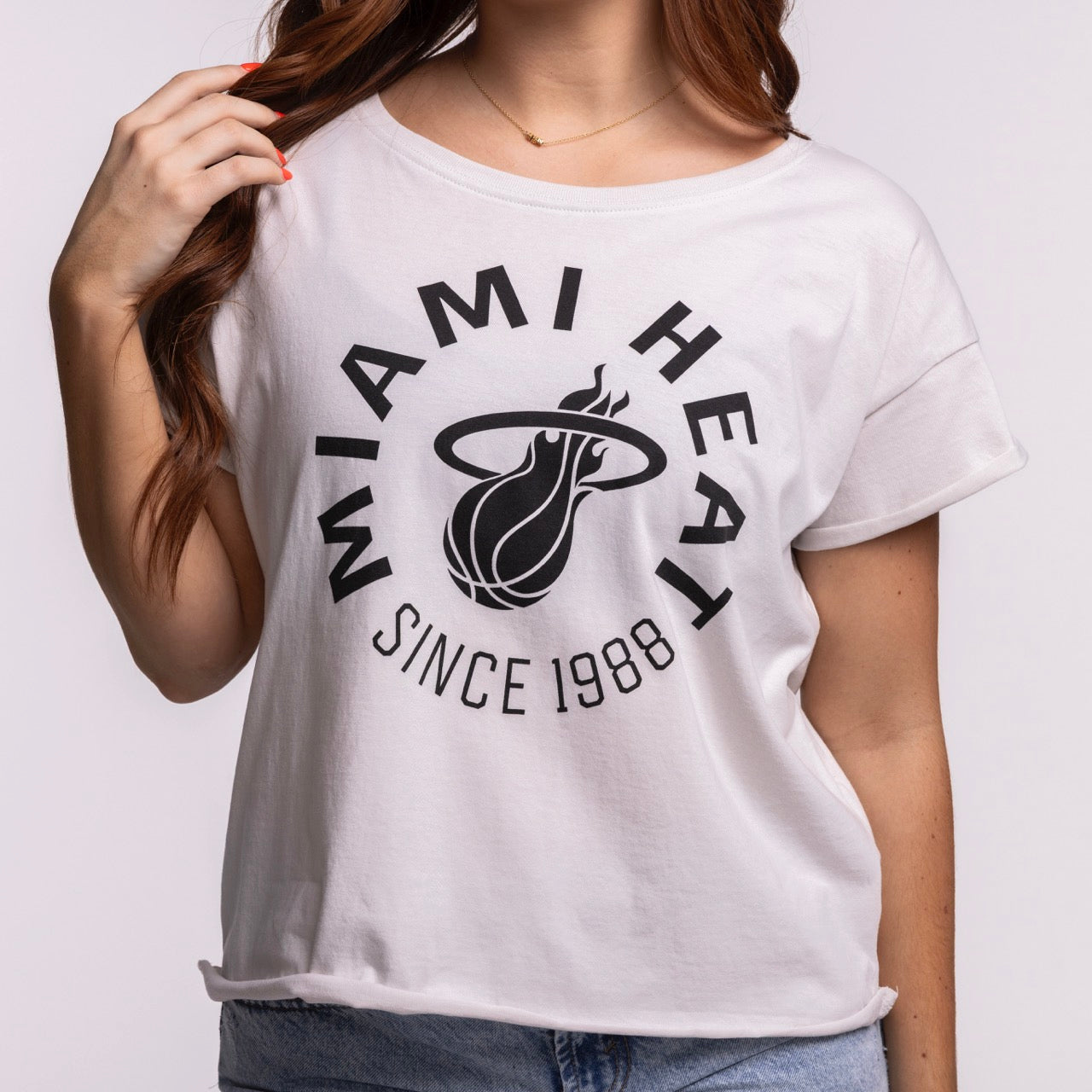 A woman wears the Sportiqe Miami HEAT 1988 Basketball Women's Tee, a relaxed fit cotton shirt with the team logo and 