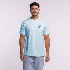 A man faces forward wearing the Court Culture Original Vice Nights "Sticker Pack" Tee by Court Culture—a standard fit, light blue 100% cotton T-shirt with a small chest logo—and light blue jeans, against a plain light background.