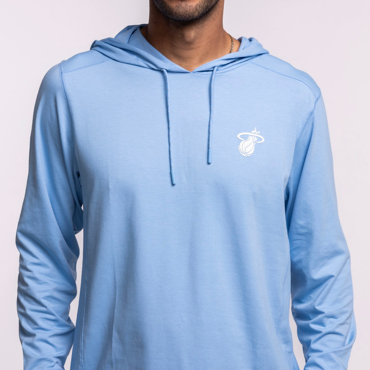 A person wears the '47 Brand Miami HEAT Original Vice Nights Blue Hoodie, featuring a small white team logo on the left chest, shown from shoulders to waist against a plain background.