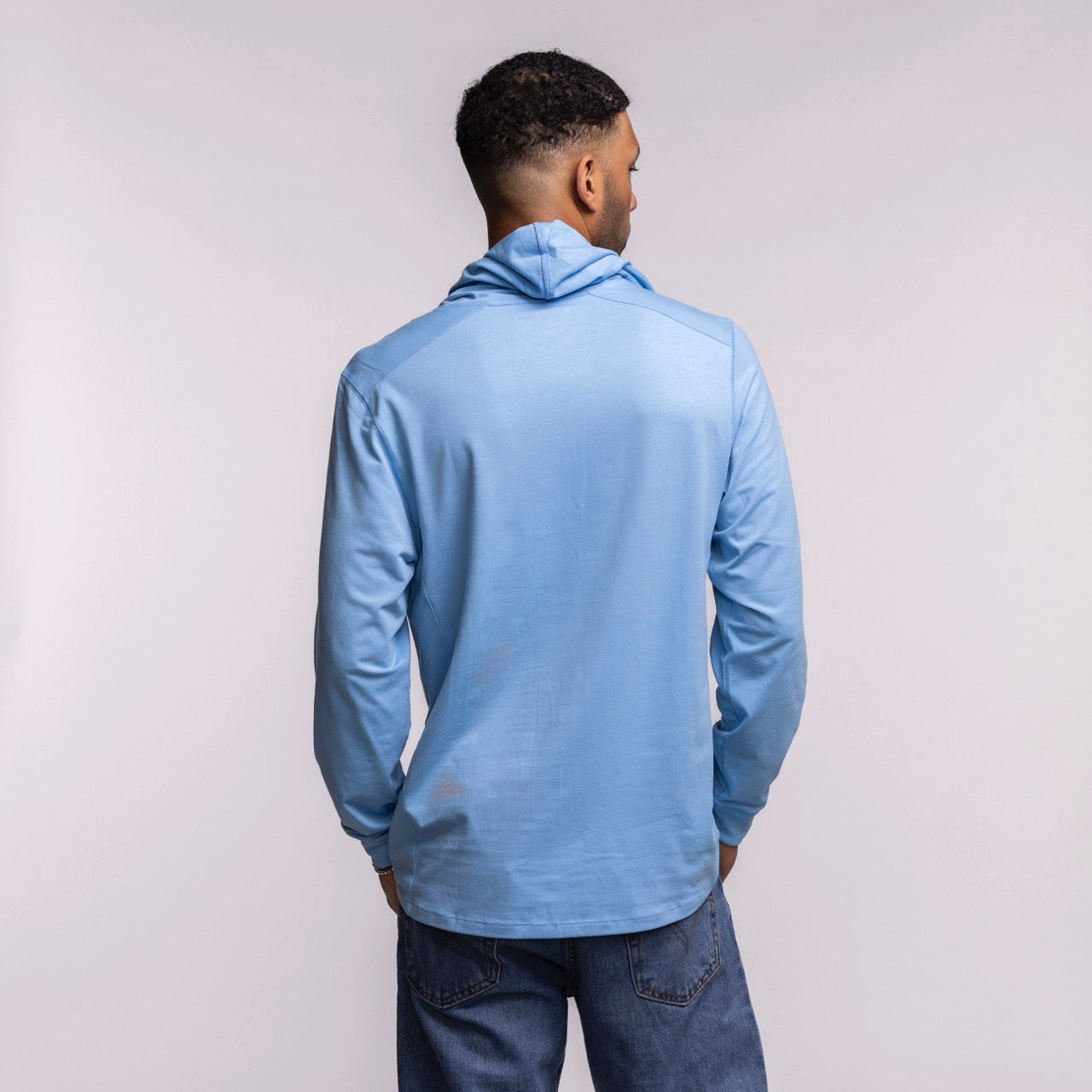 A man faces away from the camera, wearing a '47 Brand Miami HEAT Original Vice Nights Blue Hoodie and blue jeans, set against a plain light background.