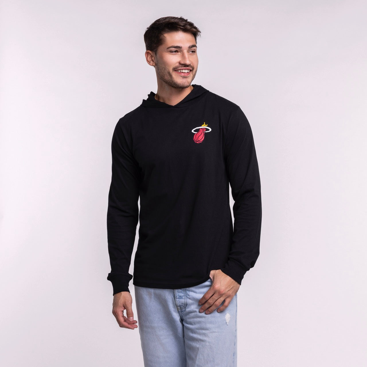 A man smiles in the Sportiqe Miami HEAT Solano Logo Hoodie by Sportiqe, featuring a black, standard fit, long-sleeve design with the Miami Heat logo. Made of 100% cotton and machine washable for easy care.