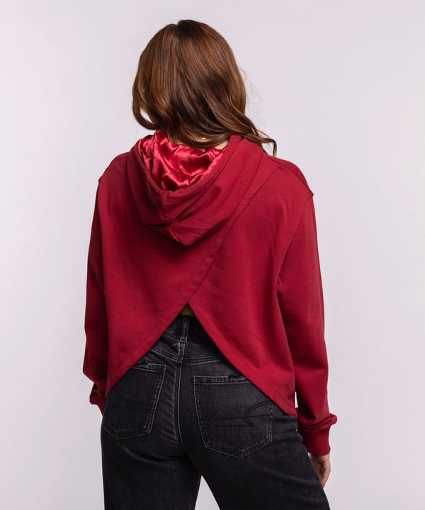 A woman with long brown hair wears the New Era Miami HEAT Open Back Women's Hoodie, featuring a basketball logo. This relaxed-fit, cropped cotton hoodie by New Era has a laid-back vibe and front pocket. Machine wash cold recommended.