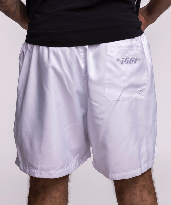 Wearing Pro Standard Miami HEAT White Out Woven Shorts, featuring Miami Heat and Milwaukee Bucks logos, hands in pockets, paired with a black t-shirt. Photo cropped mid-torso to mid-thigh. Wash with like colors for best care.
