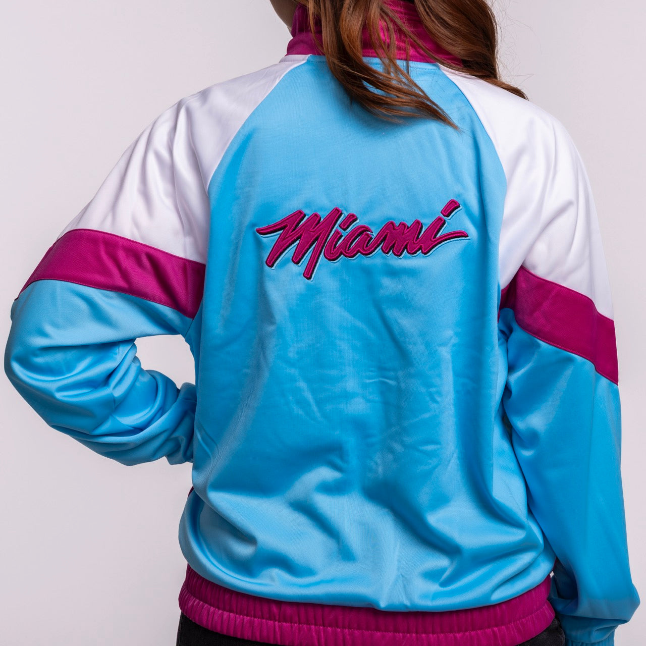 Wearing the G-III Sports Miami HEAT Original Vice Nights Women's Jacket in bright blue, white, and magenta polyester with 