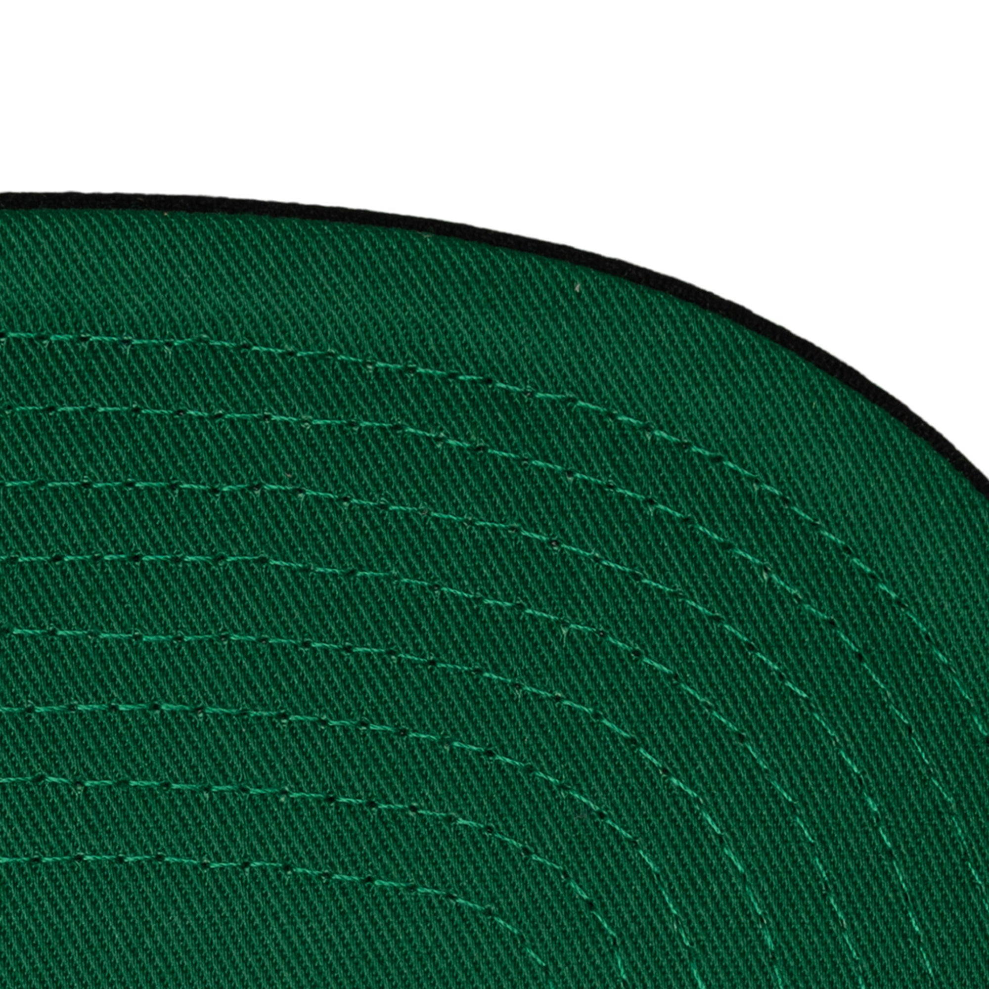 Close-up of the green underside of the Mitchell & Ness Miami HEAT Shark Tooth Snapback brim with visible concentric stitching and a black edge; spot clean only.