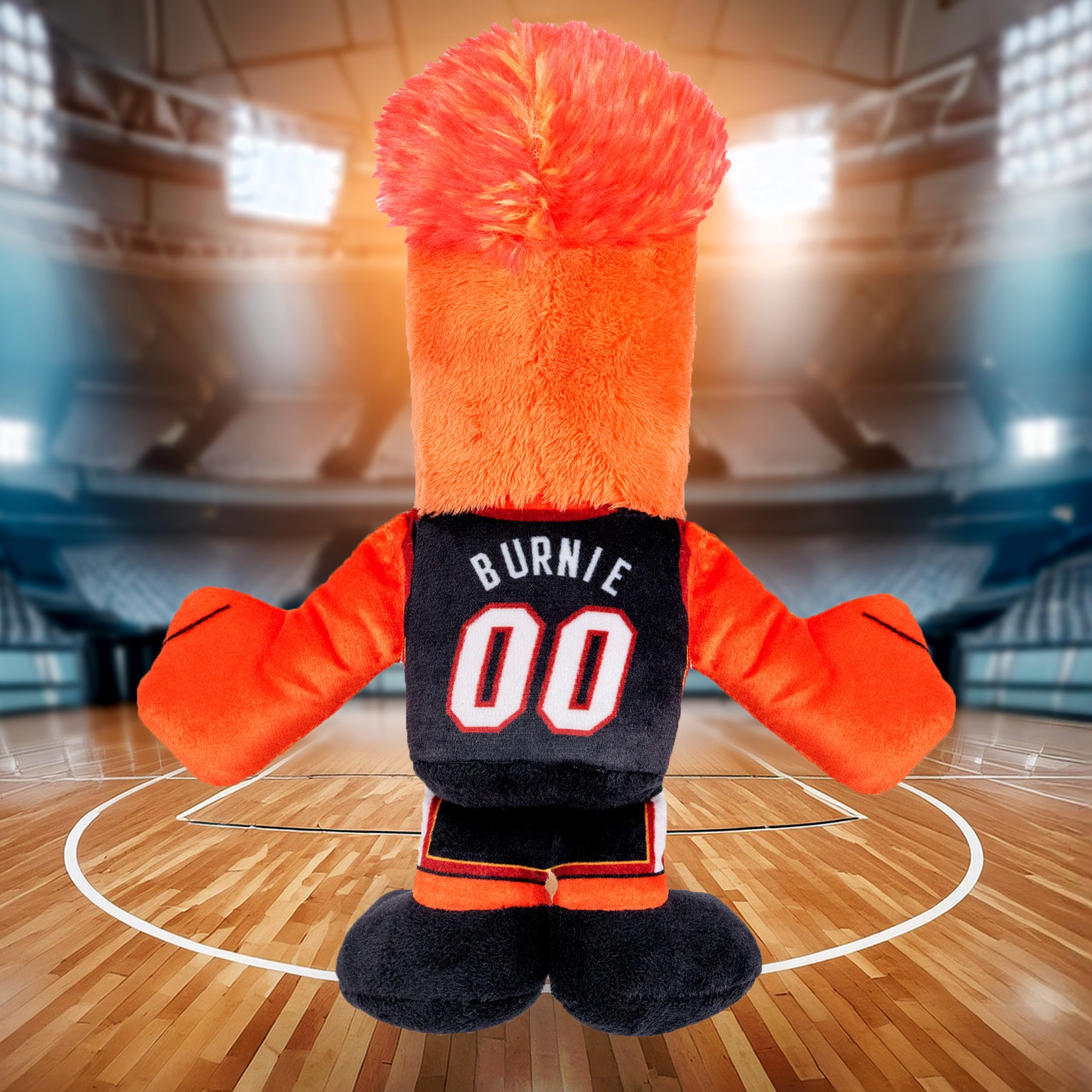 A Miami HEAT Burnie Icon Chibi Plushie by Bleacher Creatures, featuring “Burnie 00” on its jersey, stands on a basketball court in an empty arena, facing away from the camera.