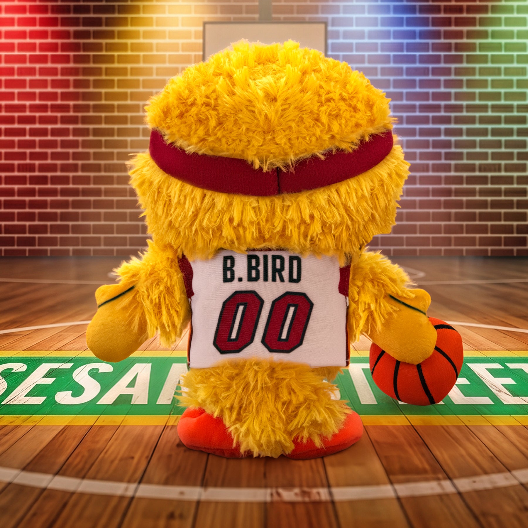 A Miami HEAT Big Bird Association Plushie by Bleacher Creatures, dressed in a basketball jersey labeled “B. Bird 00,” stands on the court holding a basketball, facing away amid colorful lights and a brick wall background inspired by classic Miami HEAT vibes.