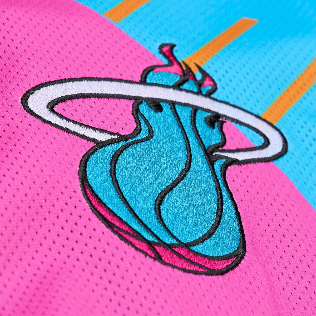 Close-up of a Miami Heat jersey with the flaming basketball logo in teal, black, and white on a vibrant pink and blue background—ideal to pair with the Court Culture x Mitchell & Ness Original Vice Nights 