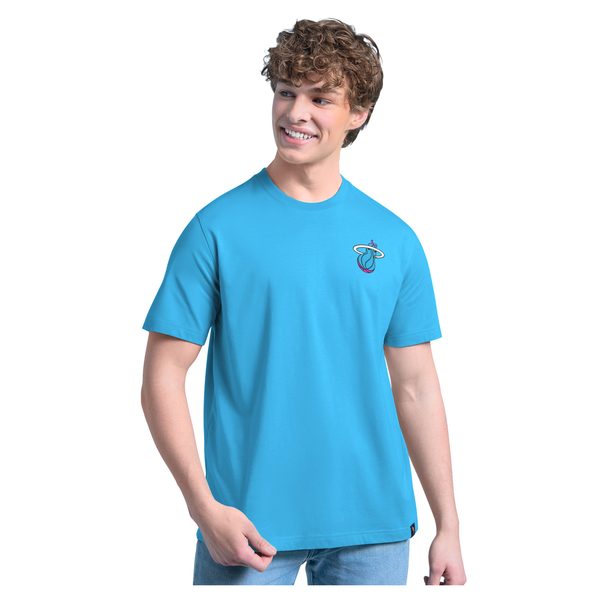 A smiling young man with curly hair wears the G-III Sports Margaritaville Miami HEAT 'Everyday is Paradise' Tee and light blue jeans, standing against a plain white background.