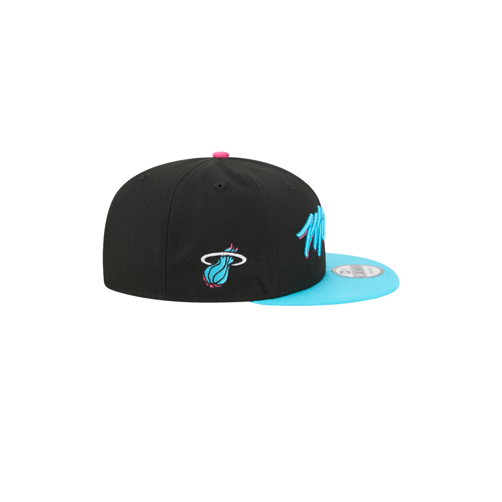 The New Era Miami HEAT Original Vice Nights Snapback features a black polyester build, turquoise flat brim, pink accents, and the Miami Heat logo on the side. One size fits most; spot clean only. Includes circular sticker under brim. Background is plain white.