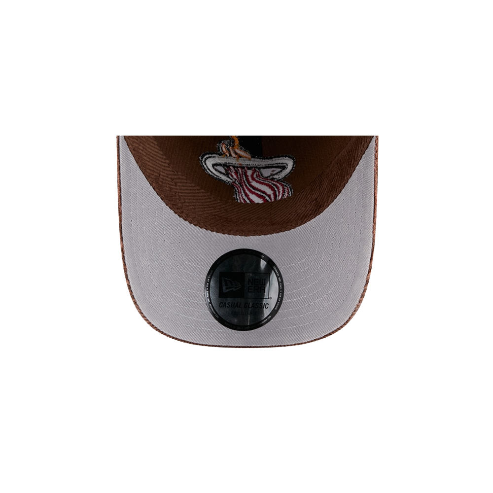 A close-up of the underside of the New Era Miami HEAT Brown Corduroy Dad Hat’s brim, featuring the Miami Heat logo and a round New Era sticker on the gray section. This cotton casual hat is designed by New Era in a one size fits most style for comfortable everyday wear.
