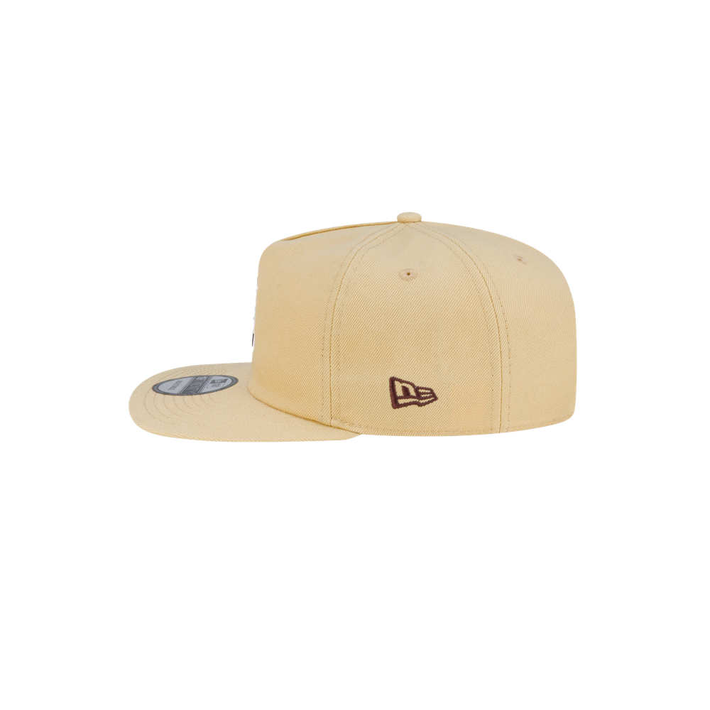 Side view of a light tan Court Culture x New Era Colada snapback hat featuring a small dark logo on the side panel.