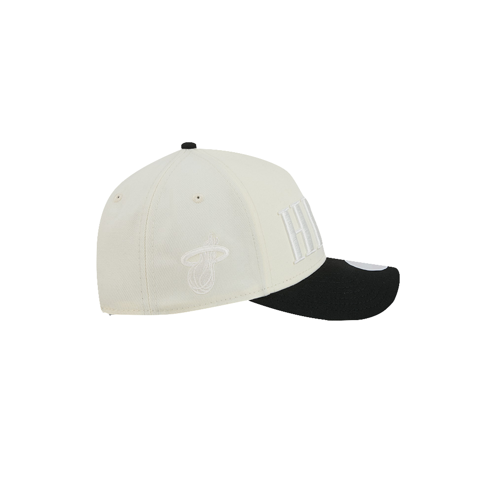 The New Era Miami HEAT 2-Tone Tonal Women’s Snapback is a white adjustable hat with a black brim, designed for an ideal fit. The front displays large white letters, while the side features a white embroidered logo. Made from high-quality polyester, this one size fits most snapback by New Era is shown on a plain white background.