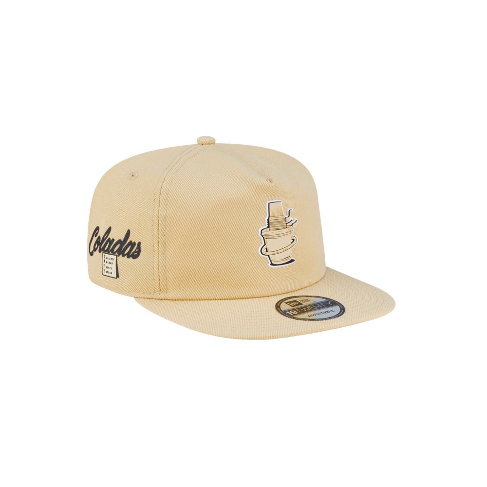 Tan polyester Court Culture x New Era Colada snapback cap featuring a cocktail graphic, script text reading Coladas, and a nutrition facts label on the side.
