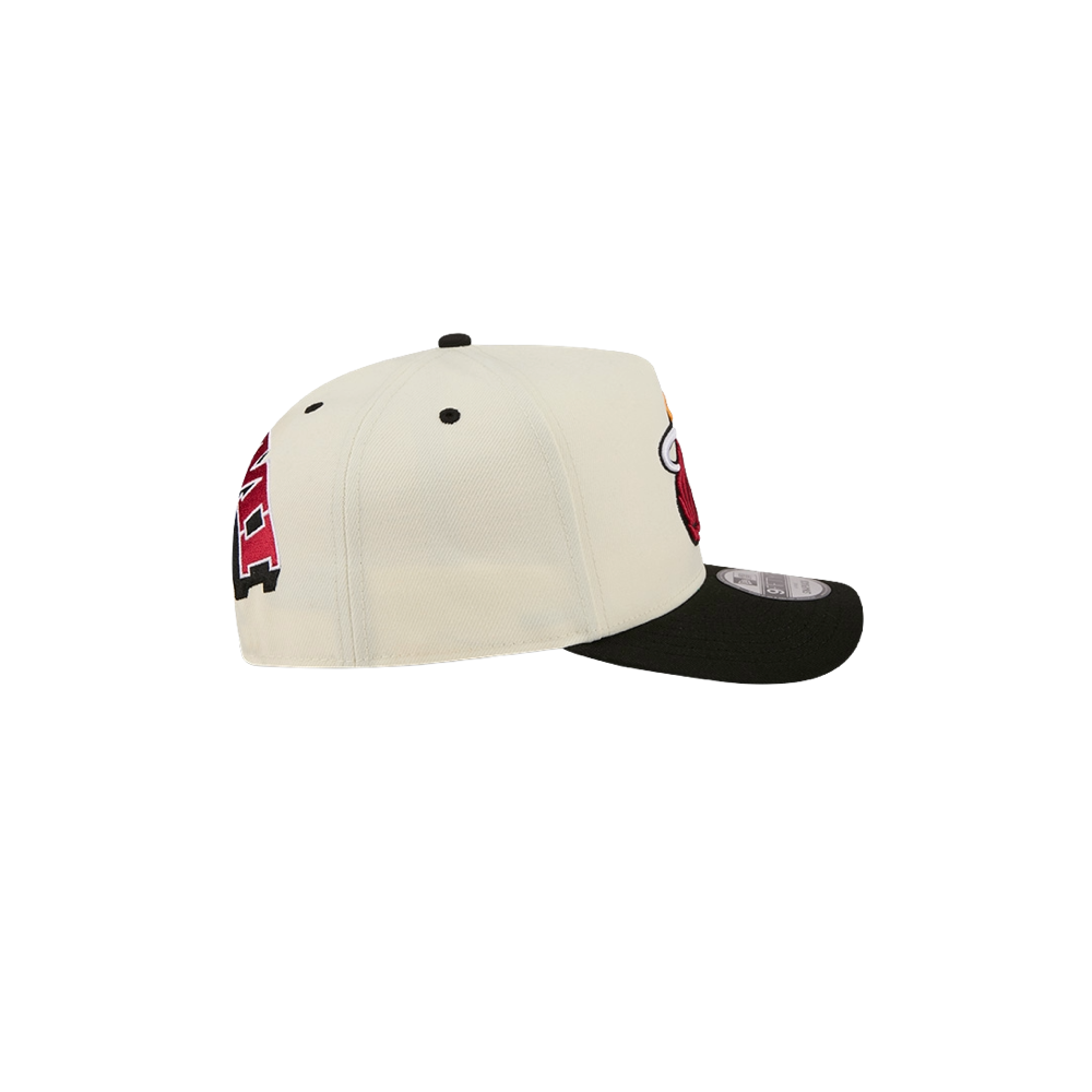 The New Era Miami HEAT Logo Wordmark Snapback by New Era is a white polyester hat with a black brim, seen from the side to display its red and black embroidered design on the front and side. This cap features ventilation holes, a slightly curved bill, and an adjustable snapback fit for most head sizes. For care, simply spot clean as needed.