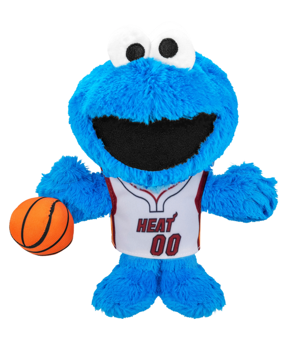 The Miami HEAT Cookie Monster Association Plushie by Bleacher Creatures is a blue plush toy featuring large eyes, a big black mouth, and a friendly expression. Dressed in a white Miami HEAT basketball jersey with “HEAT 00” and holding an orange basketball, this plush is inspired by Cookie Monster from Sesame Street.