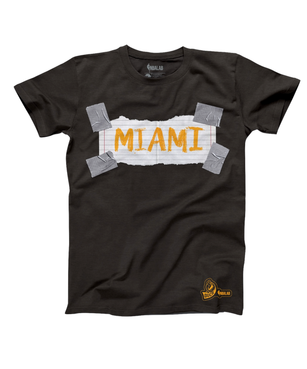 The Miami HEAT Paper Duck Tape Tee by Duck Tape is a black t-shirt featuring “MIAMI” in orange NBA style on a white, torn-paper strip held by four Duck Tape pieces. Made from recycled cotton with a small yellow logo at the lower left.