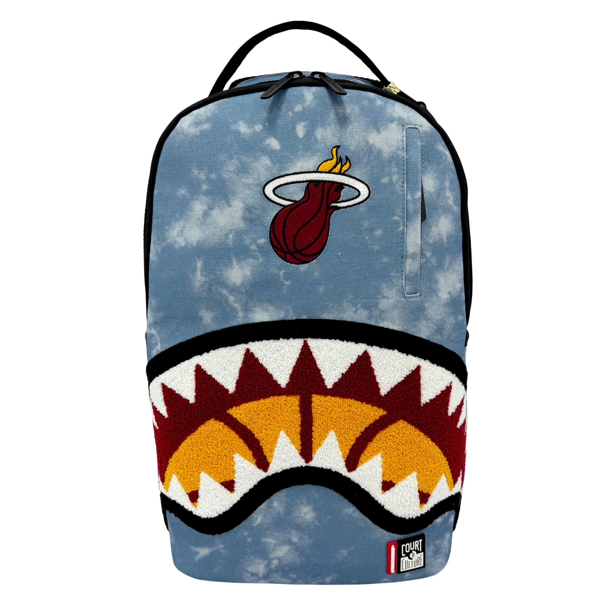 Introducing the Court Culture x Sprayground Miami HEAT Tie-Dye Jaw Backpack by Sprayground—a limited edition piece crafted from blue denim and showcasing an embroidered Miami Heat logo at the top, along with a bold shark mouth design over an orange basketball graphic on the front.