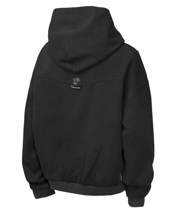 The Nike Miami HEAT Oversized Logo Fleece Youth Hoodie by Nike showcases a large multicolored Miami Heat logo in red, white, black, and yellow on the front with a small white Nike swoosh above it. Made from a comfortable cotton-polyester blend, this black hoodie features a loose fit, classic kangaroo pocket, and is photographed against a plain white background.