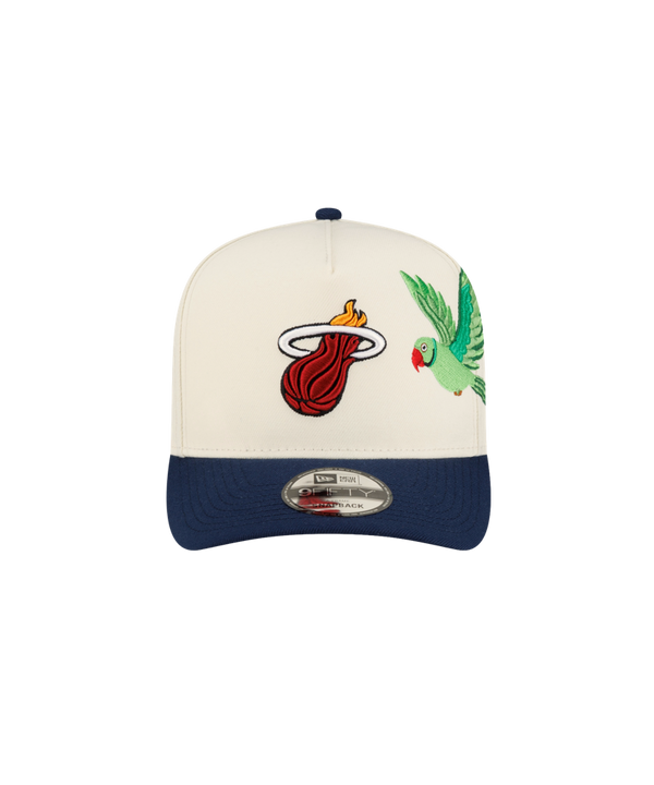 Court Culture x New Era Parakeet snapback hat in cream with a blue brim, featuring an embroidered flaming basketball logo and a green parakeet on the front panels.