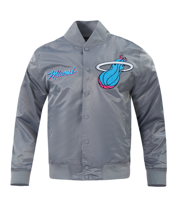 The Pro Standard Miami HEAT Original Vice Nights Satin Jacket is a shiny gray polyester bomber with a large, colorful Miami Heat logo on the left chest and “Miami” in blue and pink script on the right. Features snap button front, ribbed cuffs/hem, standard fit.