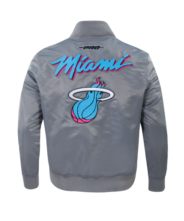 The Pro Standard Miami HEAT Original Vice Nights Satin Jacket is a shiny gray polyester bomber with a large, colorful Miami Heat logo on the left chest and “Miami” in blue and pink script on the right. Features snap button front, ribbed cuffs/hem, standard fit.