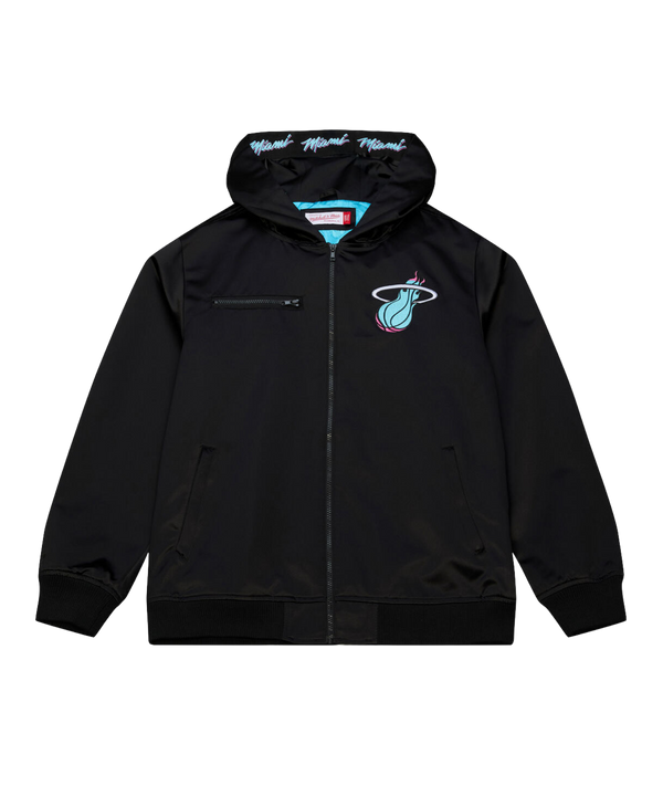 The Mitchell & Ness Miami HEAT Original Vice Nights Satin Bomber is a black zip-up jacket with hood, featuring teal and pink team logo on the chest and 