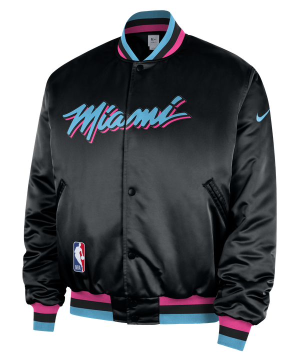 The Nike Miami HEAT Original Vice Nights Bomber Jacket features black satin polyester, “Miami” in blue and pink script on the front, blue and pink trim, NBA logo patch, Nike swoosh sleeve detail, and insulated synthetic fill.