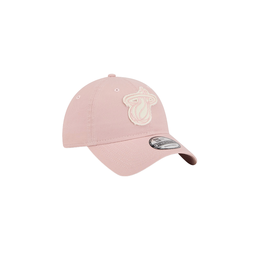 The New Era Miami HEAT Pink Stamp Dad Hat is a light pink cotton cap with an embroidered tongue and lips logo, curved brim, and manufacturer's sticker. One size fits most; spot clean for best care.