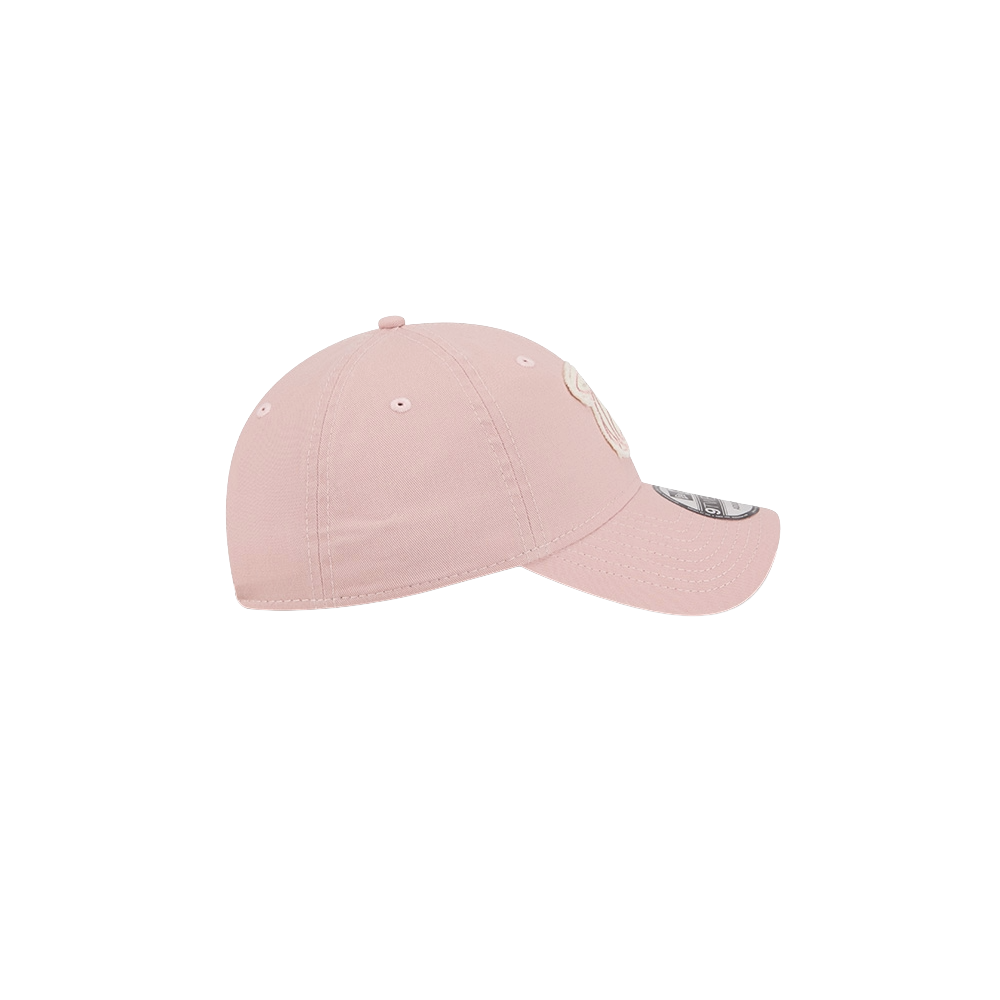 The New Era Miami HEAT Pink Stamp Dad Hat by New Era is light pink cotton with ventilation eyelets and a curved brim, shown from the side on a plain white background. One size fits most; spot clean for best care.