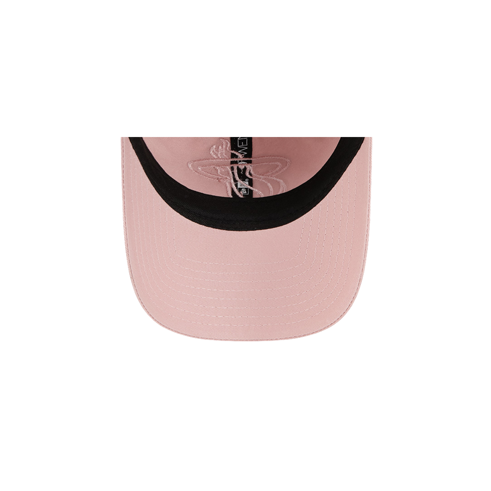 Top-down view of the New Era Miami HEAT Pink Stamp Dad Hat by New Era, featuring light pink cotton, a black inner band, visible stitching on the brim, and part of the interior label. Plain white background. One size fits most; spot clean recommended.