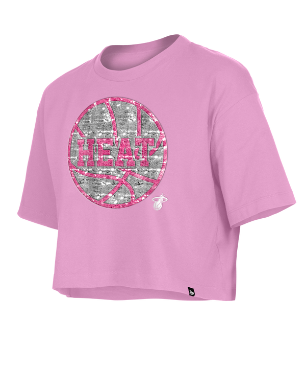 The New Era Miami HEAT Basketball Sequins Girls Tee is a light pink, cropped cotton T-shirt with a glittery basketball graphic, HEAT lettering, and a Miami Heat logo. This standard fit tee is machine washable and perfect for a relaxed look.