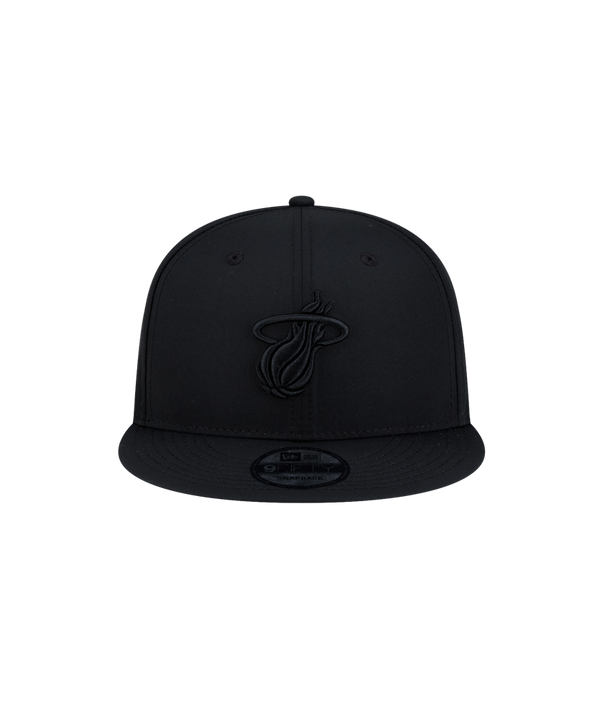 Court Culture x New Era Blackout Snapback hat in black, featuring a matching black Miami Heat logo on the front and a circular sticker on the flat brim.