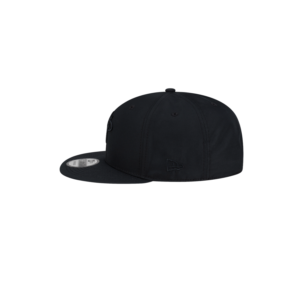 Side view of a black polyester Court Culture x New Era Blackout snapback cap with a flat brim.