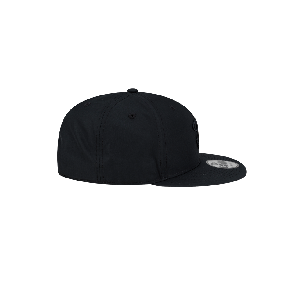 Profile view of a Court Culture x New Era Blackout snapback hat featuring a polyester construction and a flat brim.