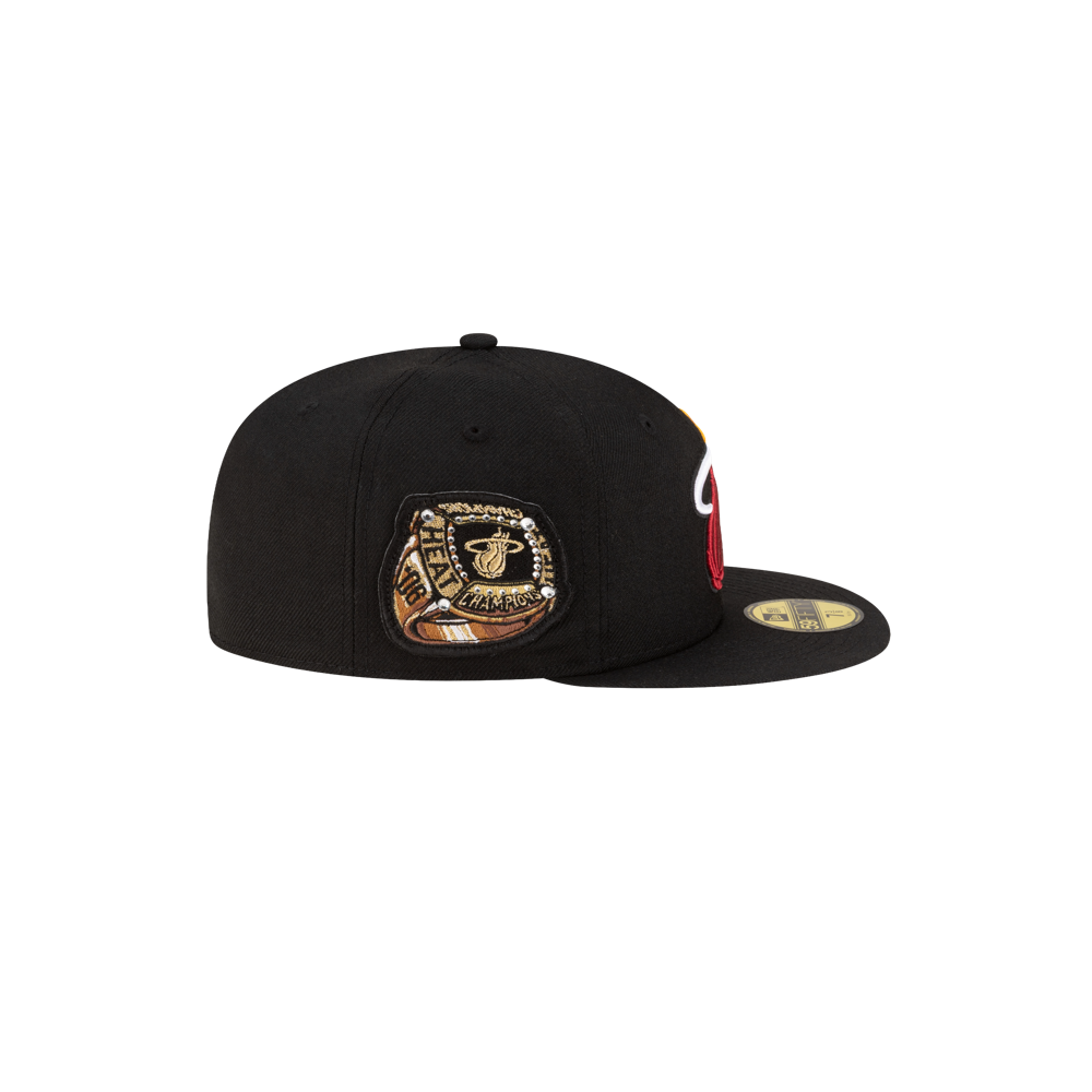 The New Era Miami HEAT 06' Ring Fitted Hat is a black wool cap with a gold Miami Heat championship ring patch on the side and a flat brim. Spot clean only. Brand: New Era.