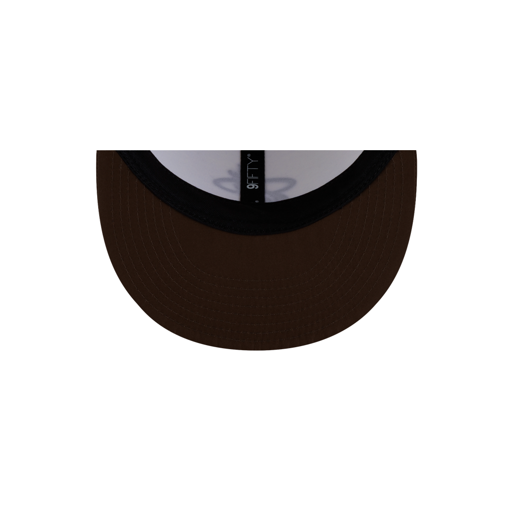 Close-up view from underneath the brown brim of a Court Culture x New Era Café y Leche Snapback, showing a 9FIFTY size sticker on the one size fits most polyester hat.