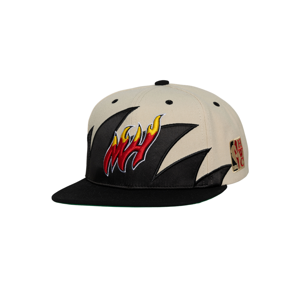 The Mitchell & Ness Miami HEAT Shark Tooth Snapback is a beige and black flat-brim polyester hat with a bold flame front, red and yellow team logo, NBA side patch, adjustable fit (one size fits most). Spot clean to maintain freshness.