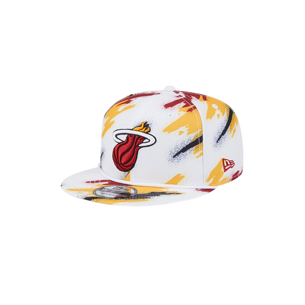 The New Era Miami HEAT Youth Paint Snapback is a white polyester cap with yellow, red, and black brushstroke patterns, featuring the Miami Heat logo on the front and a small red New Era logo on the side. One size fits most; spot clean recommended.