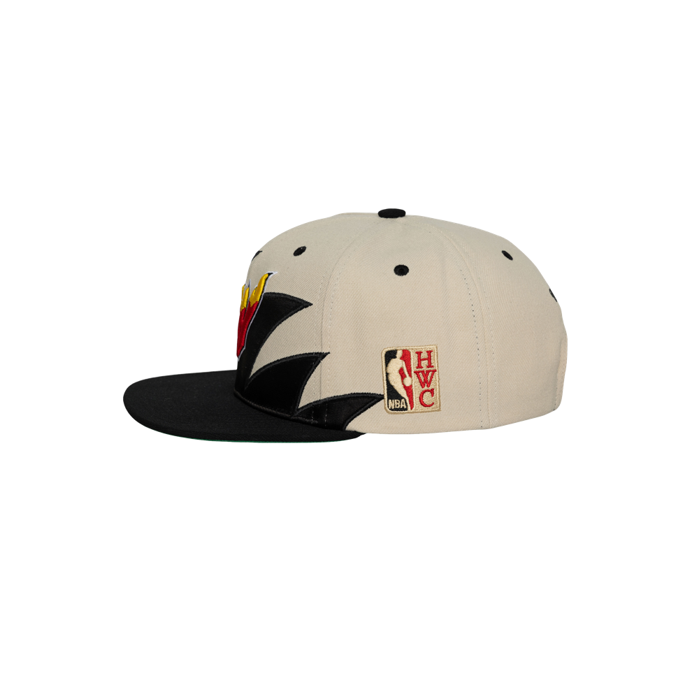 The Mitchell & Ness Miami HEAT Shark Tooth Snapback features a beige and black polyester build, jagged black side design, front team logo, NBA Hardwood Classics patch, adjustable snapback fit, and is spot clean recommended.