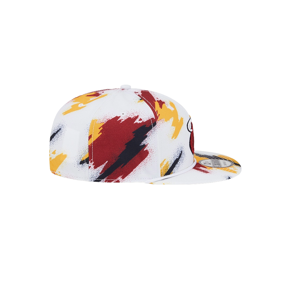 The New Era Miami HEAT Youth Paint Snapback by New Era is a white polyester cap with bold red, yellow, and black abstract paint streaks. Shown side view on a white background. One size fits most; spot clean recommended.