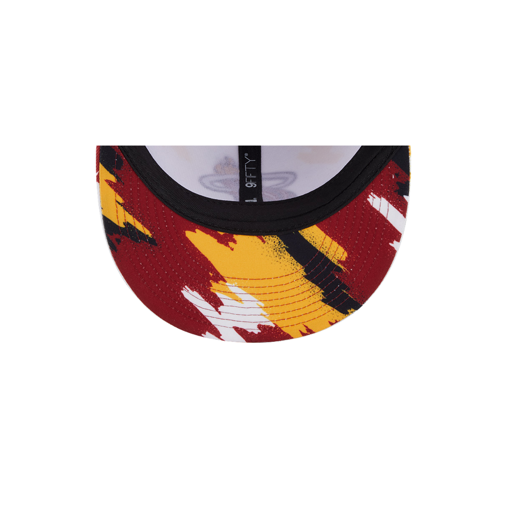 A close-up of the New Era Miami HEAT Youth Paint Snapback's polyester brim shows a red, yellow, black, and white abstract pattern. The sweatband and crown are visible—one size fits most; spot cleaning is easy.