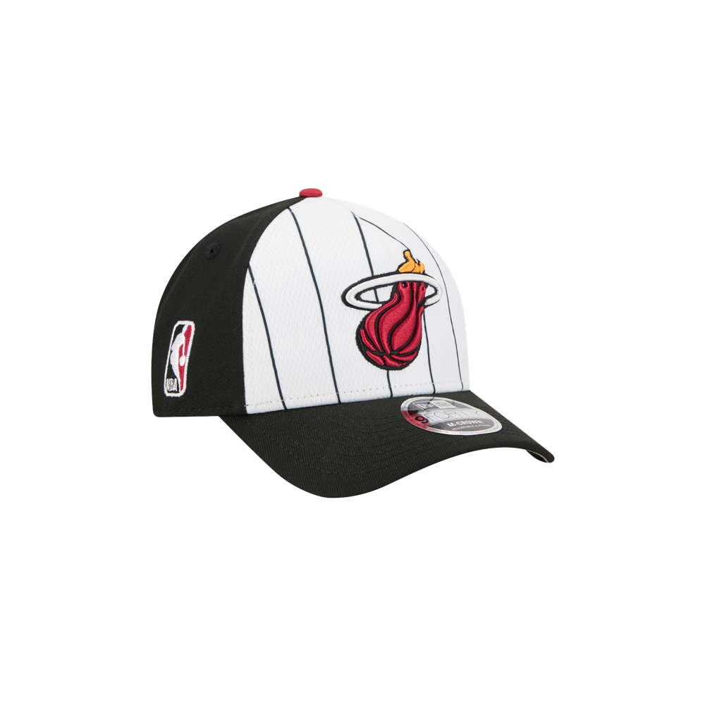 The New Era Miami HEAT 2025 Tipoff Snapback is a black and white pinstriped cap featuring the team logo on the front, an NBA logo on the side, and a curved black brim.