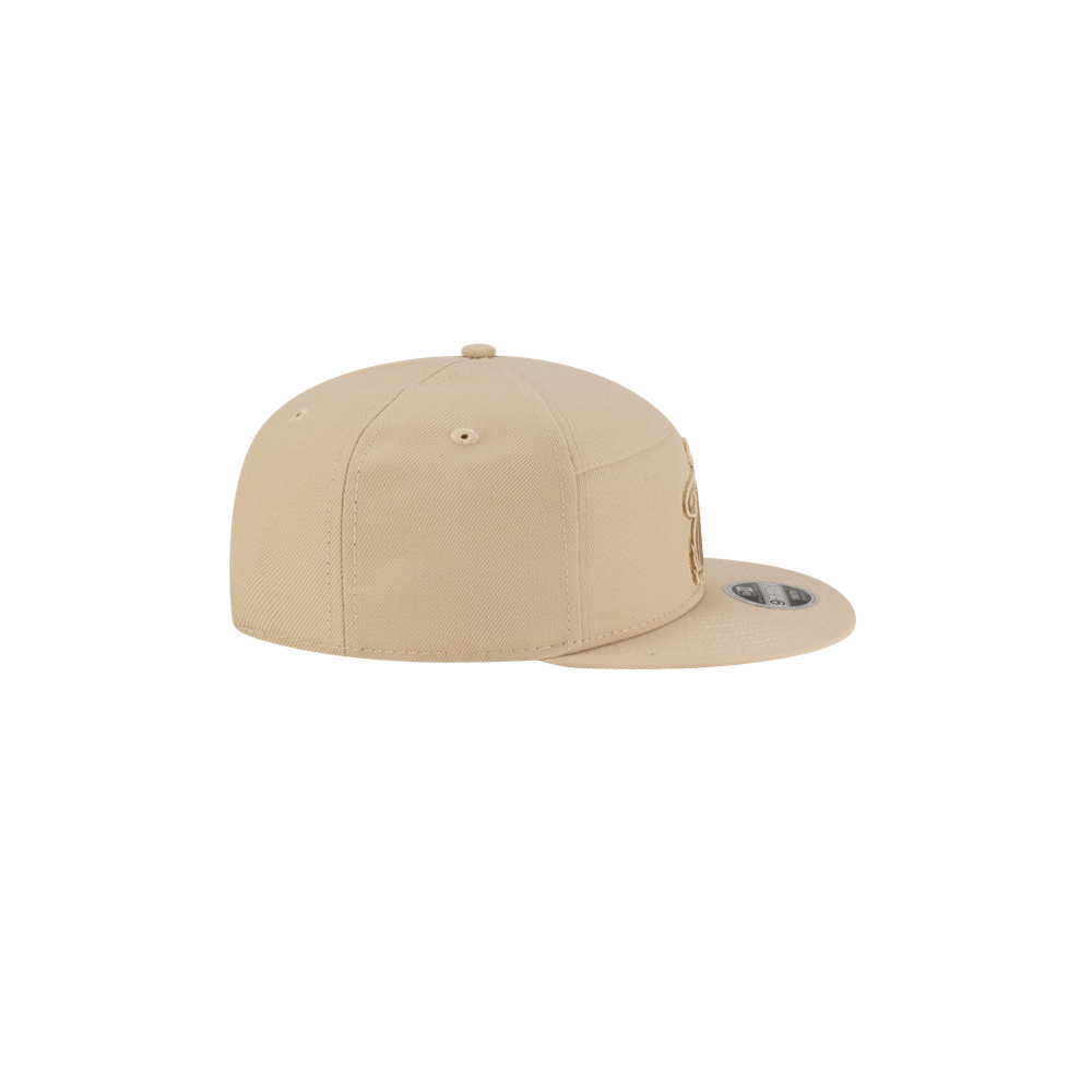 The New Era Miami HEAT Tan Youth Snapback is a beige polyester flat-brim baseball cap, shown from a rear side angle on a white background. One size fits most and easy to spot clean.