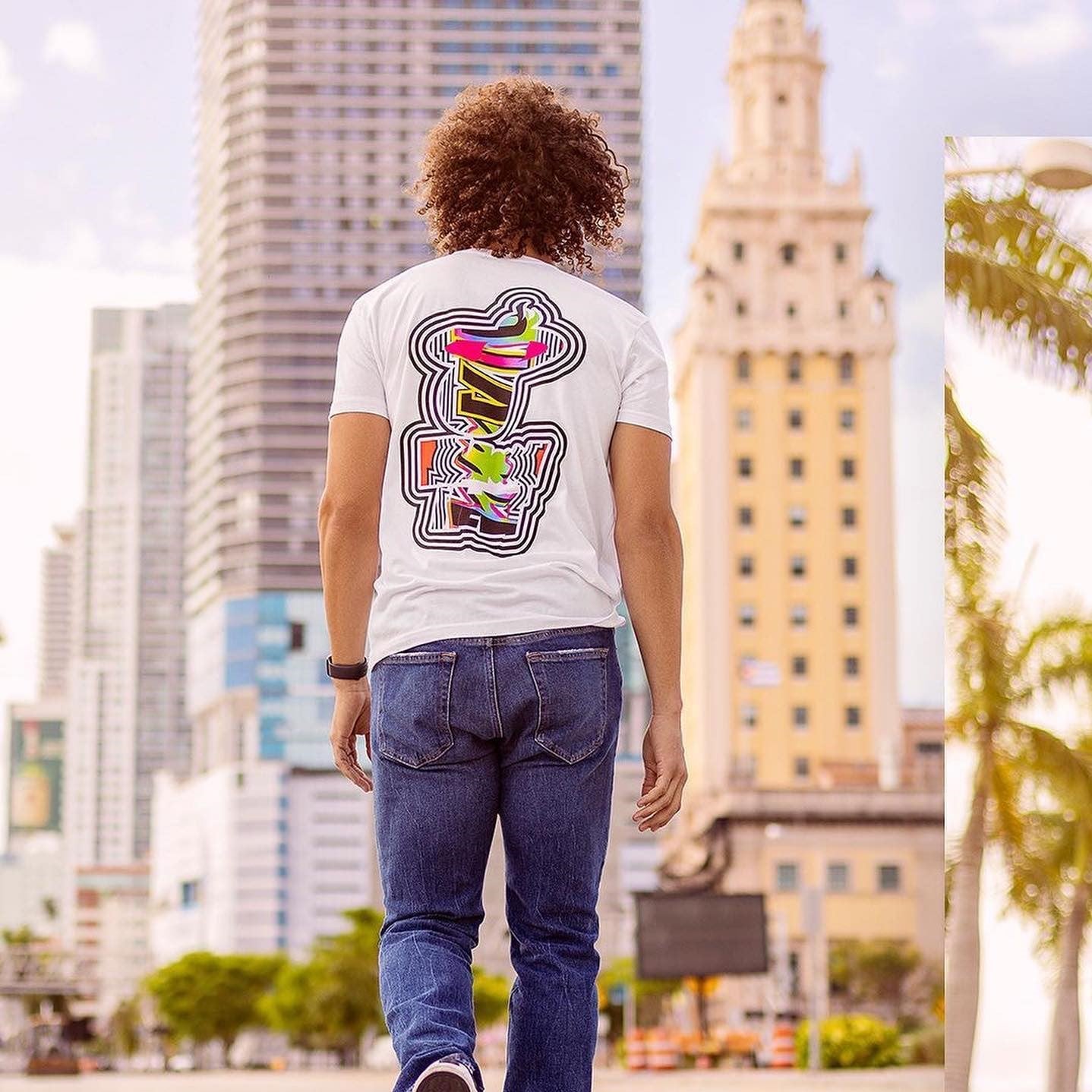 White Court Culture Playoff Chaos tee with colorful Miami HEAT graphic on back, worn with blue jeans outdoors. - Court Culture Playoff Chaos Men’s Tee